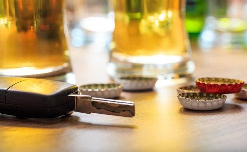 Car keys next to beer bottle caps and glasses of beers